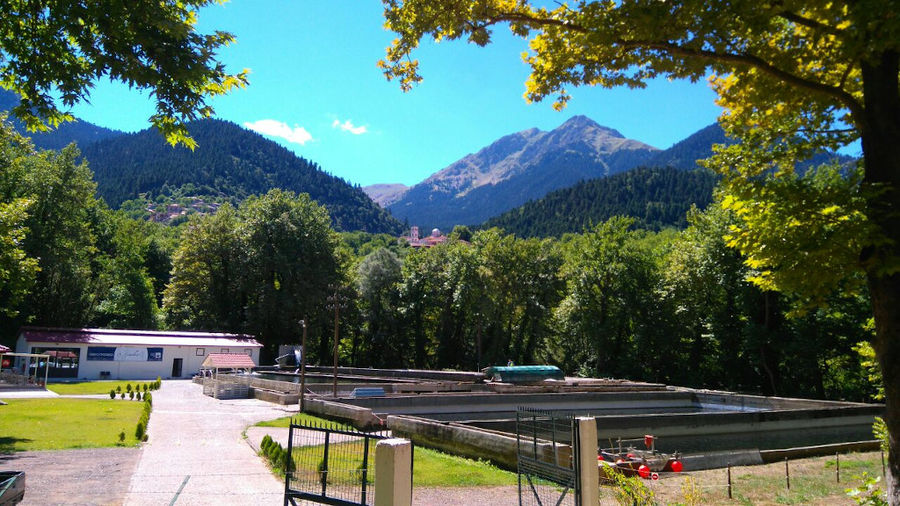 far view of ponds fish crops and buildings surrounded by trees and mountains at 'Fresko'